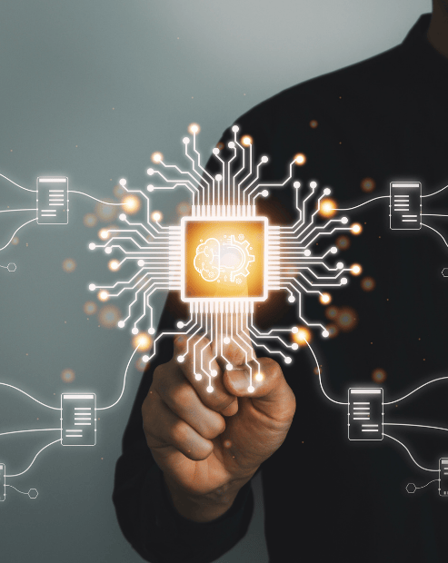 A person in a dark shirt points their finger toward a glowing digital graphic centered on a stylized microchip. The chip contains an icon of a human brain merged with a gear. White digital lines and data-point icons branch out from the center against a dark, moody background, symbolizing the intersection of human creativity and systematic technology.