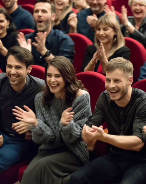 Small promo image for the Find Your Audience Workshop. A diverse group of people sitting in a theatre with red seats, smiling and clapping enthusiastically. The foreground features four young adults—two men and two women—laughing and applauding, representing an engaged and appreciative audience.