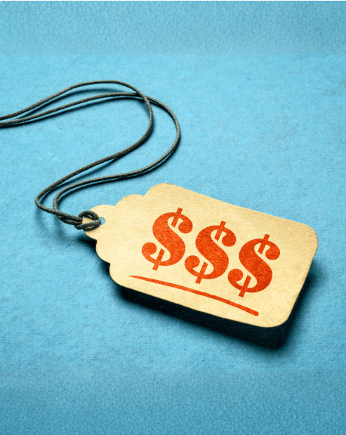 Small hero image promoting the What's it Worth Workshop. A close-up, high-angle shot featuring a tan, vintage-style paper price tag lying on a textured vibrant blue surface. The tag is tied with a dark, thin string that loops upward. Stamped onto the tag in bold, reddish-orange ink are three large dollar signs ($$$) underlined by a single horizontal stroke.