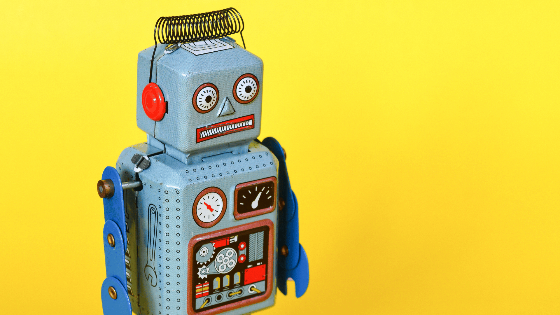 Close-up of a retro light-blue tin robot toy with dials, gears, red ears, and a wire coil antenna against a solid yellow background, representing AI Protocols for Creative Business.
